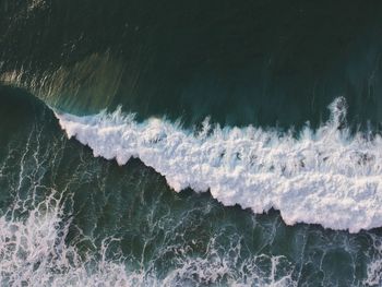 Close-up of sea waves rushing towards snow
