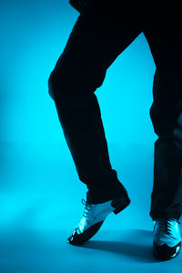 Low section of man standing against blue background