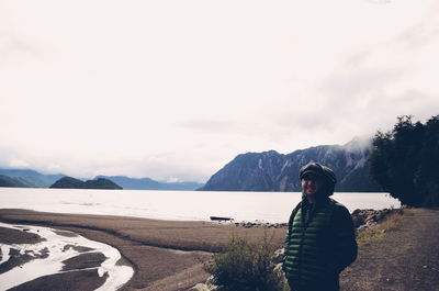 Portrait of young woman standing by sea against sky