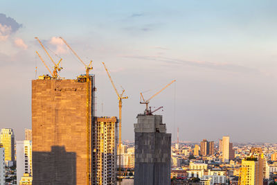 Cranes at construction site against sky during sunset