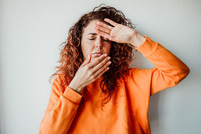 Sick woman with eyes closed standing against wall