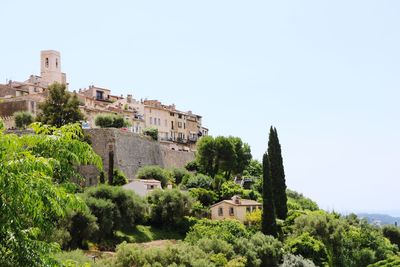 Buildings by trees against clear sky