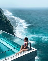 Young woman in swimming pool against sea