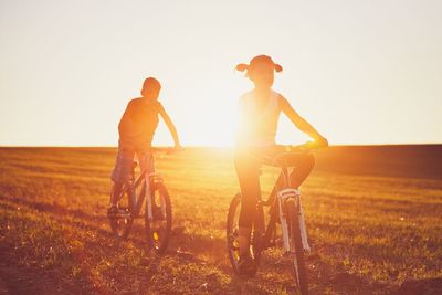 People riding bicycle on field against clear sky