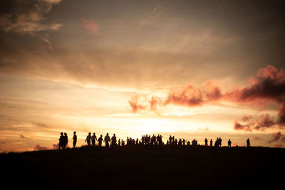 Silhouette people on field against sky during sunset