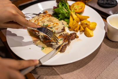 Cropped hand of person having food in plate