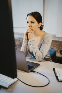 Young female programmer brainstorming over computer in office