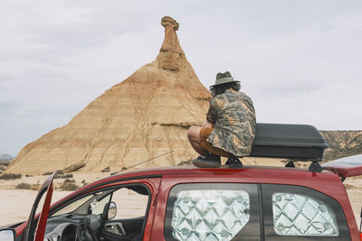 Traveler sitting on top of a van taking photos of the rocky landscape of the navarra desert person