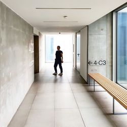 Rear view of man walking in corridor of building