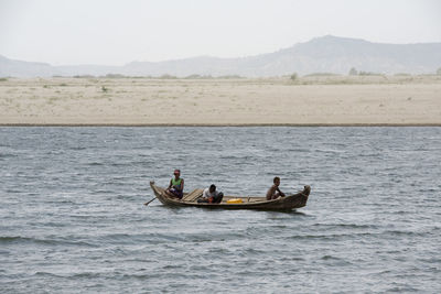 Boys in boat on lake against sky