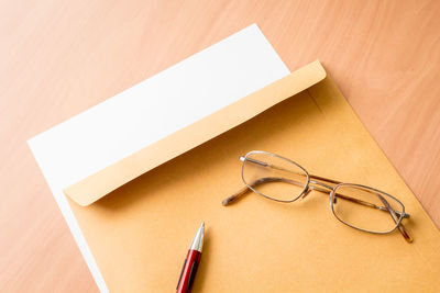 High angle view of envelopes with eyeglasses and pen on wooden table