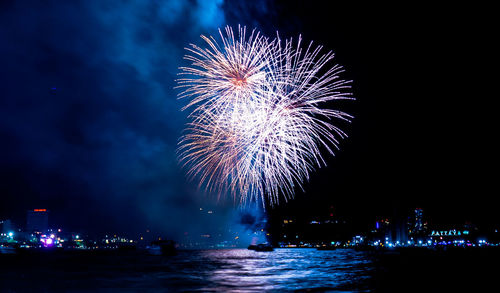 Firework display in city against sky at night