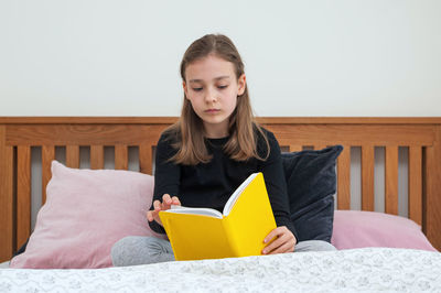 Portrait of young woman using laptop while sitting on bed at home