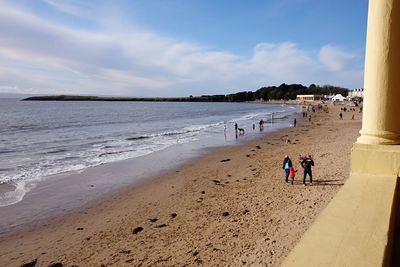 People on beach against cloudy sky