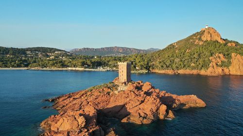 Rock formations by sea against clear blue sky