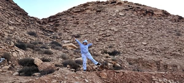 Full length of woman dancing on rock formation against sky