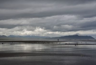 Scenic view of beach against cloudy sky