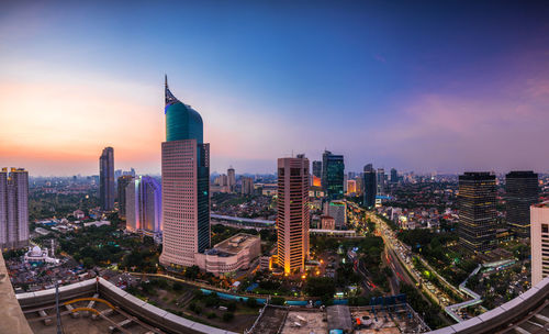 Aerial view of illuminated city buildings during sunset