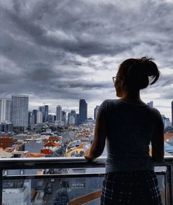 Rear view of woman looking at city buildings against sky