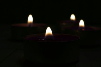 Close-up of lit candles in darkroom