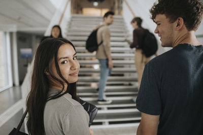 Portrait of smiling female student with friend in university