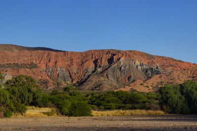 Scenic view of arid landscape against clear blue sky