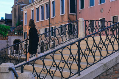 Rear view of woman standing on railing against buildings