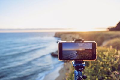 Close-up of digital camera on beach against sky