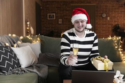 Smiling young man sitting on sofa at home