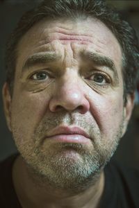 Close-up portrait of mature man against black background