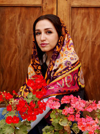 Portrait of woman in headscarf with flowers against wood