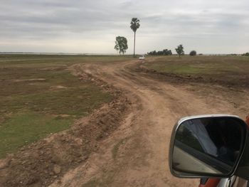 Road by field against sky