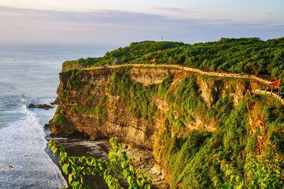 Cliff by sea against sky