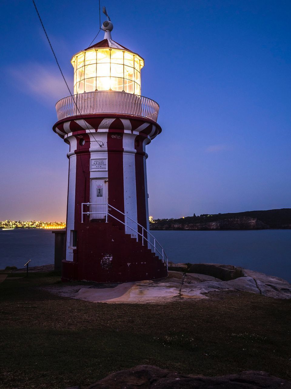 LIGHTHOUSE AMIDST BUILDINGS AGAINST SKY AT DUSK