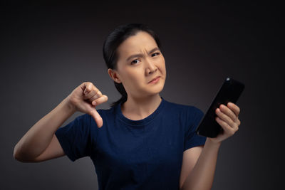 Young woman using mobile phone against black background