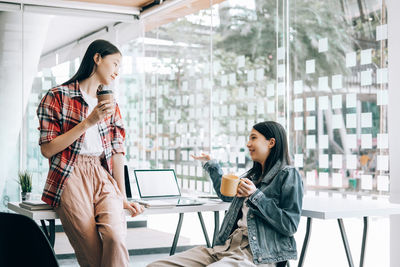 Young woman using mobile phone while sitting on table