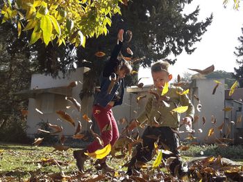 Children standing on field against trees