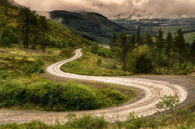 Scenic view of road by mountains against sky