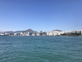 Sea by buildings against clear blue sky