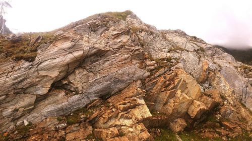 Low angle view of cliff on mountain against sky