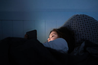 Rear view of woman sitting on bed at home