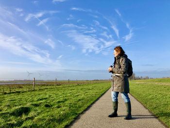 Full length of woman standing on field against sky