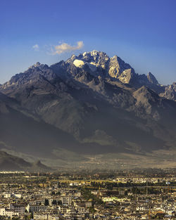 Aerial view of townscape by mountains against sky