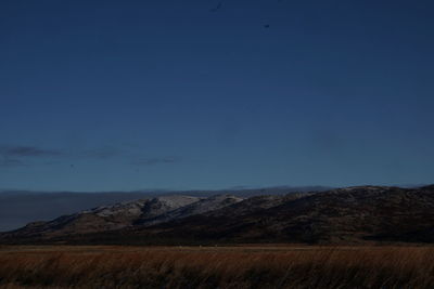 Scenic view of landscape and mountains against blue sky