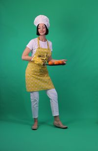 Full length portrait of smiling woman standing against blue background