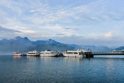 Boats in sea with mountain range in background