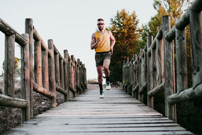 Full length of young man on footbridge against sky