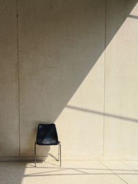 Shadow of chair on tiled floor against wall