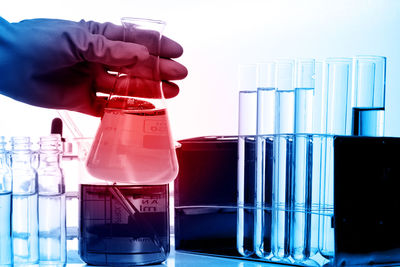 Cropped hand of scientist holding chemical in flask at laboratory