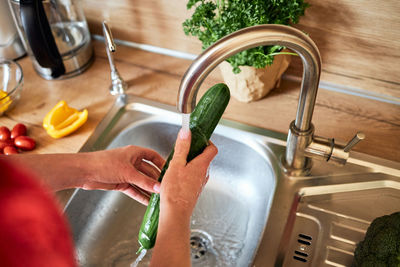 Cropped hand washing hands in sink